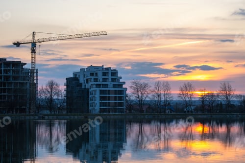 Preview: Tower crane and high residential apartment buildings under construction on lake shore. Real estate