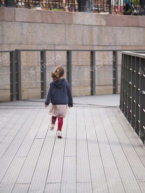 Preview: A little girl runs along a wooden bridge in summer day, back view.