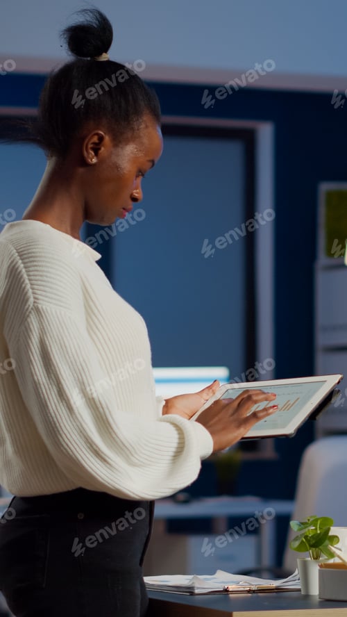 Preview: Black woman employee standing in office and analysing charts