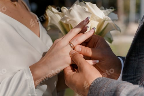 Preview: Groom putting golden ring on bride's finger during wedding ceremony. Hands with rings close up