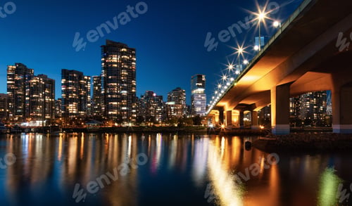 Preview: Cambie Bridge in False Creek with modern city buildings at night after sunset.