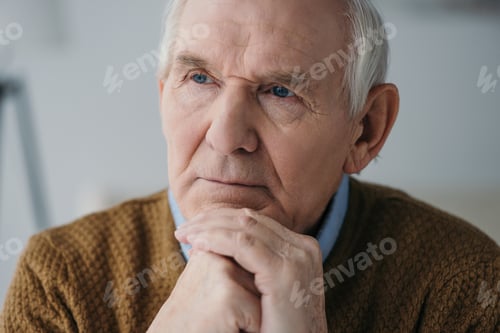 Preview: Senior thoughtful man leaning on hands in light room