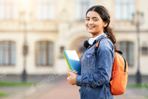 Preview: Contented young Indian academic lady with course materials and backpack