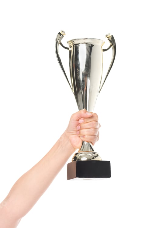 Preview: partial view of female hand holding champion cup isolated on white