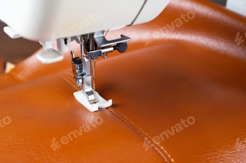 Preview: Modern sewing machine presser foot with a needle sews brown leather