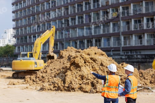 Preview: Two construction workers discuss progress at an urban site