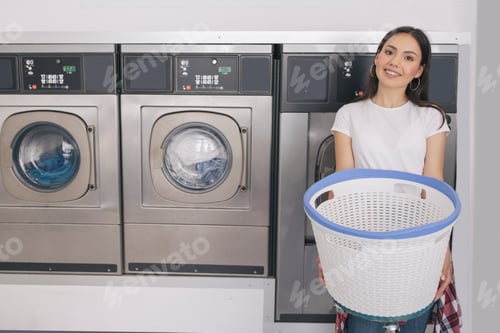 Preview: Cheerful Woman Advertising Laundry Service Posing Near Washing Machines Indoors