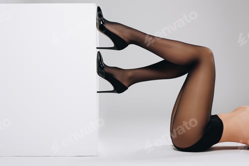 Preview: Female legs in black pantyhose on white background