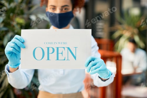 Preview: Close-up of waitress inviting people to come in at reopened cafe during coronavirus pandemic.