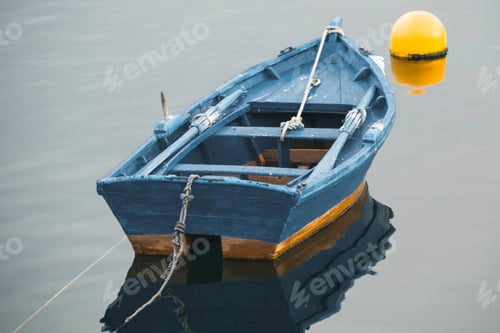 Preview: Small blue fishing boat in front of a yellow buoy on a calm sea
