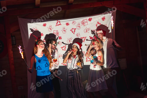 Preview: Friends blowing party whistles and holding sparklers at New Year's party