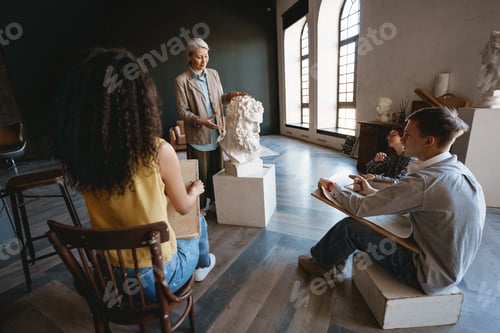Preview: Mature teacher talking with her students during class in art school