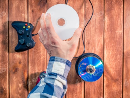 Preview: hand choosing a video game to play compact disk on the wooden table
