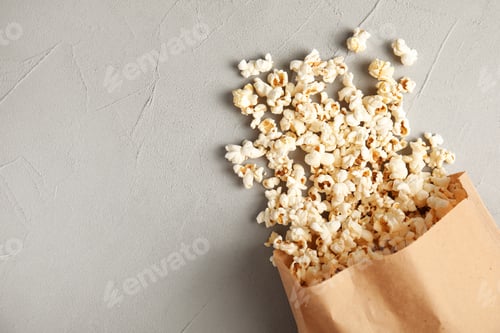 Preview: Paper bag with tasty popcorn on grey background, top view