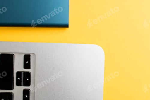 Preview: Closeup of a laptop edge and a hard drive on yellow background