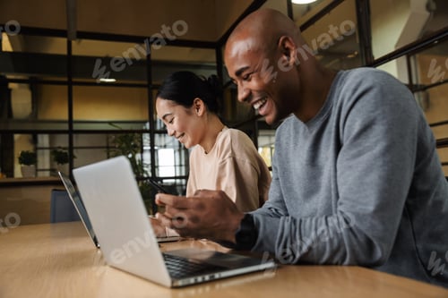 Preview: Image of multiethnic young coworkers working on laptops in office