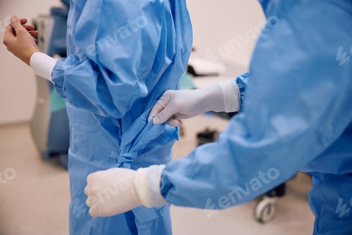 Preview: Close up of nurse tying doctor's surgery gown in operating room.