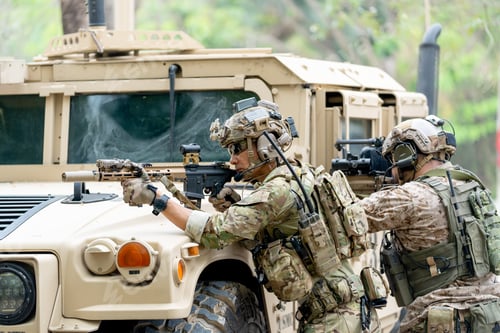 Preview: Wide shot of two militaries or soldiers stay in front of humvee car area of car hood and point gun