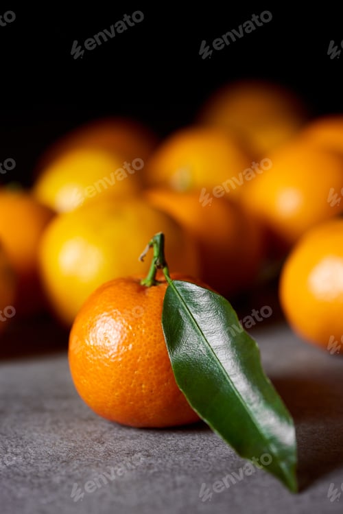 Preview: selective focus of sweet clementine near tangerines with green leaf