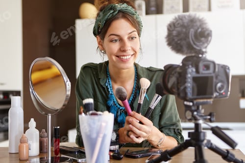 Preview: Smiling happy woman representing three kinds of new cosmetic brushes, selling her ptoducts through o