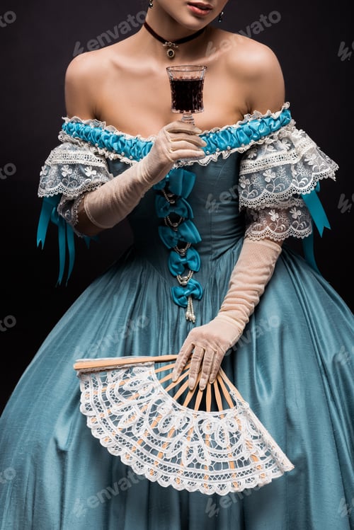 Preview: cropped view of victorian young woman holding wine glass and fan on black
