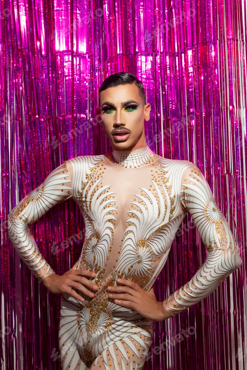 Preview: young drag queen with short hair and mustache posing with fuchsia color background