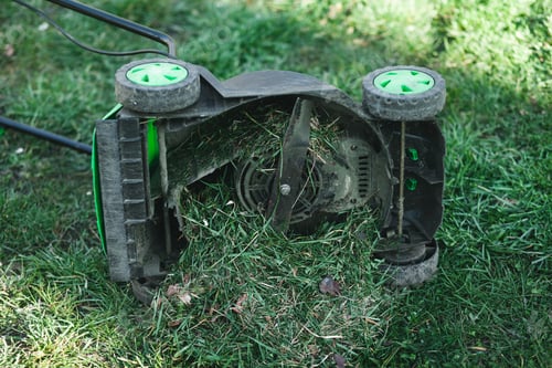 Preview: Lawn mower overflowing with grass lies on its side