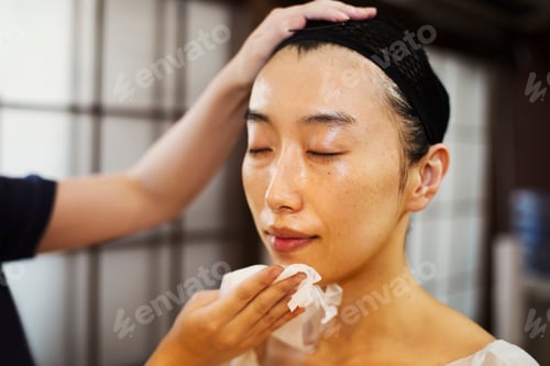 Preview: A geisha or maiko with a hair and make up artist creating the traditional hair style and make up