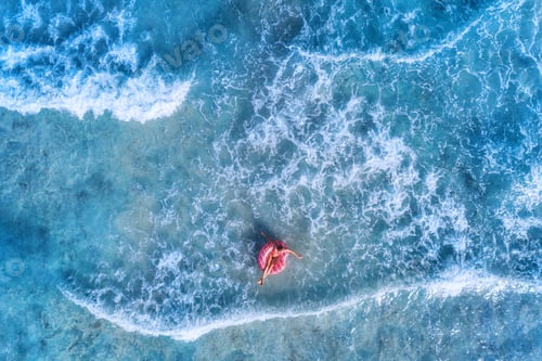 Preview: Aerial view of a young woman swimming with the donut swim ring