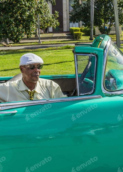 Preview: Havana, Cuba - November, 22 2012: Black man sitting in retro car on street