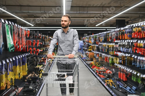 Preview: male builder in a hardware store chooses a tools