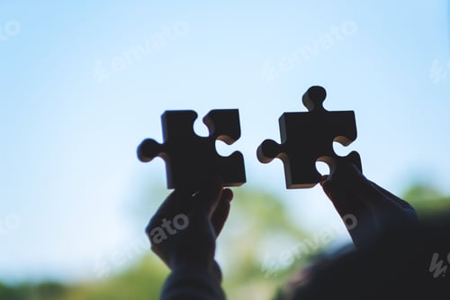 Preview: Closeup image of a woman holding and putting a piece of wooden jigsaw puzzle together