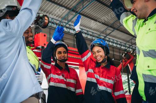Preview: Team engineers and foreman stack hand and shake hands to show success at factory machines.
