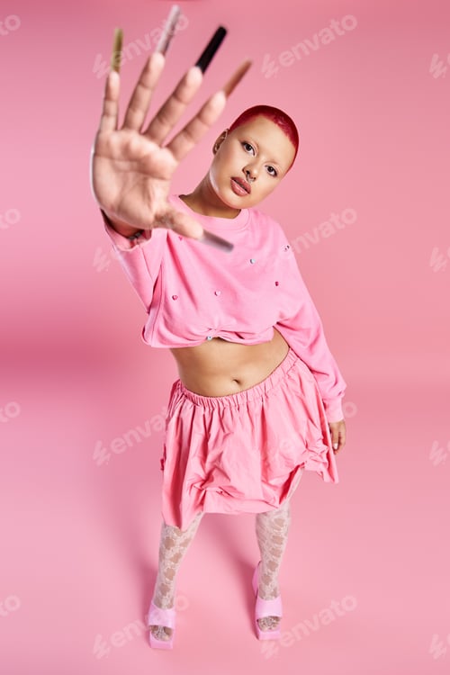 Preview: A young woman with short pink hair flaunts her daring style in a vibrant studio setting