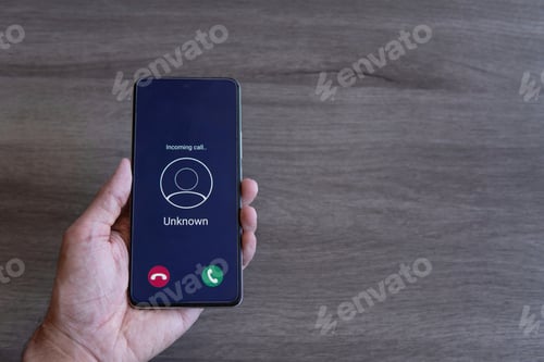 Preview: Top view image of hand holding smartphone and unknown incoming phone call on the screen.