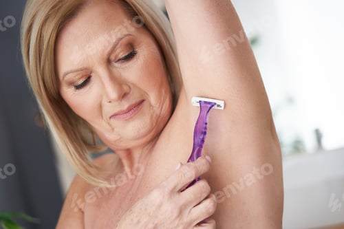 Preview: Senior woman shaving armpits in the bathroom