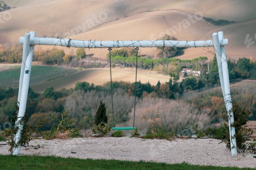 Preview: Picturesque swing nestled in lush green grass against a backdrop of majestic mountains