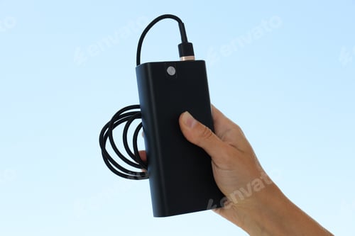 Preview: Powerbank with cord in female hands on blue background
