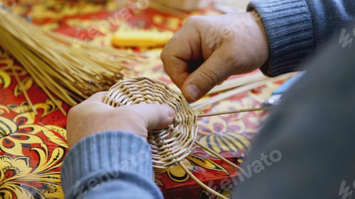 Preview: Hands weaving the bottom of a straw basket. ART. A man weaves a round part of straw and twigs with