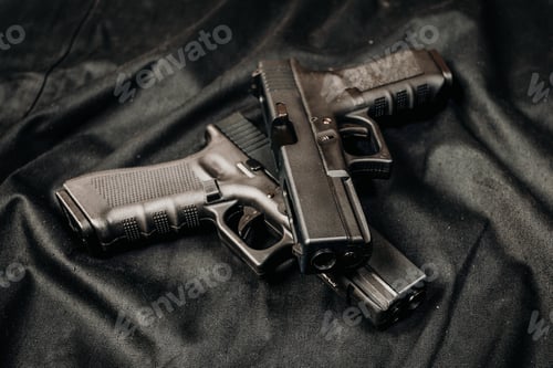 Preview: Two handguns placed on a dark surface showing the details of the firearms clearly during daytime