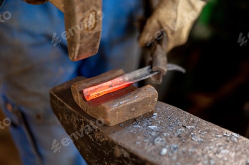 Preview: The blacksmith in production process of metal products, handmade in the forge. Craftsman heats metal