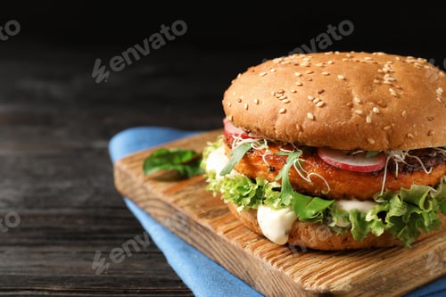 Preview: Board with tasty vegetarian burger on wooden table