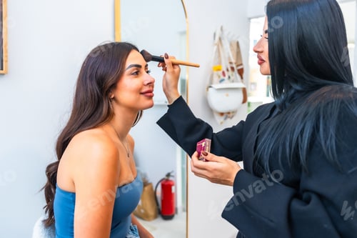 Preview: Makeup artist applying foundation on client's face in beauty salon