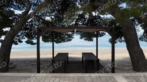Vista previa: Outdoor seating area under trees in the shade at the beach with water view