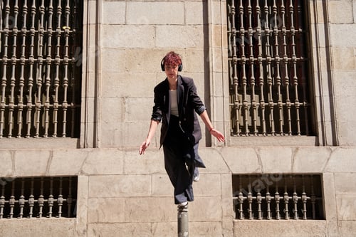 Preview: A woman is standing on a pole and wearing headphones. He is wearing a black jacket and blue pants