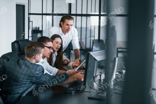 Preview: Analysing information. Team of stockbrokers works in modern office with many display screens