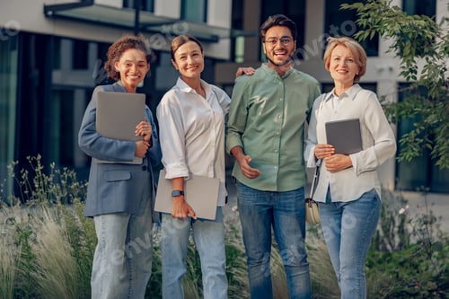 Preview: Group of diverse business people standing on background of modern office building and looks camera