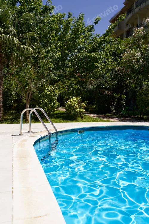 Preview: Pool with blue water in the courtyard of the house against the backdrop of greenery