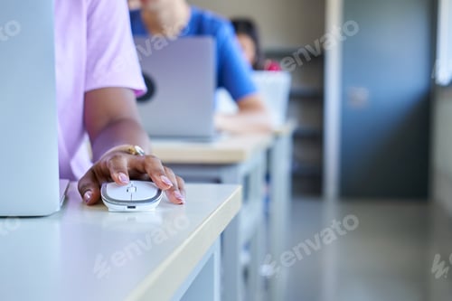 Preview: Close up of dark skin hand using computer mouse at classroom, unrecognizable girl and colleagues.