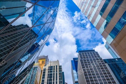 Preview: Bottom view of modern skyscrapers in business district against blue sky